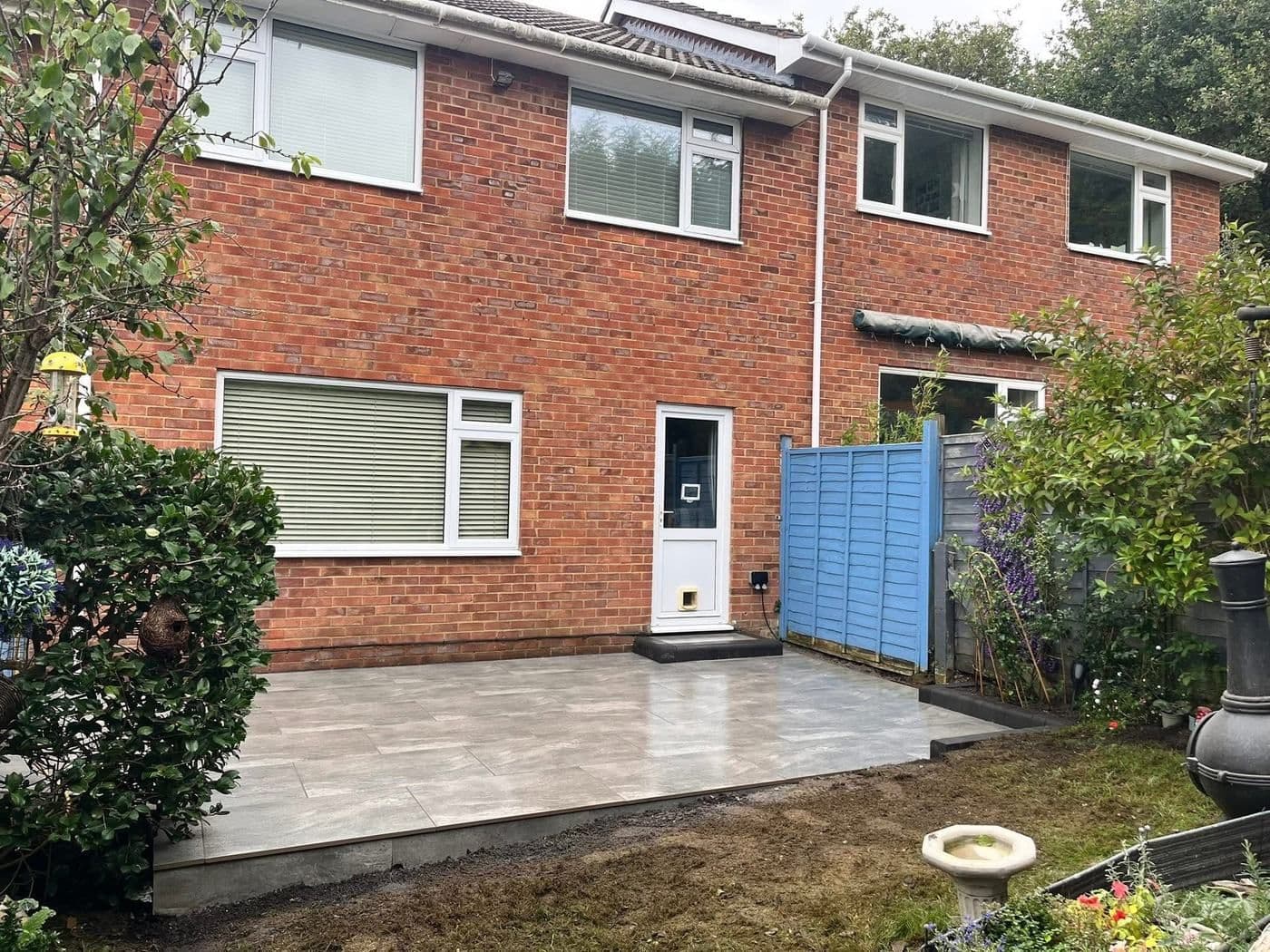 After: the same rear garden with a new full-width grey porcelain patio
